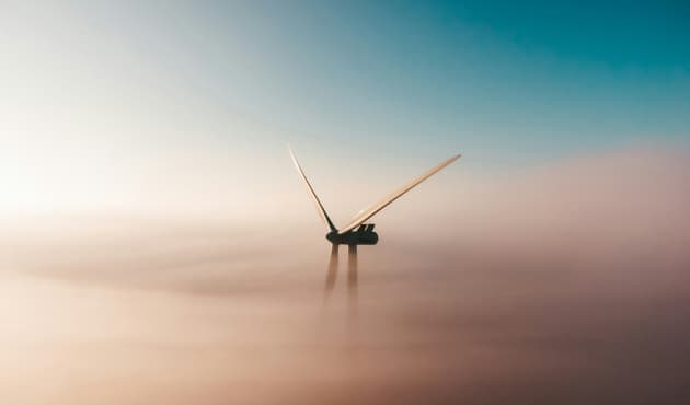 A wind turbine partially obscured by mist